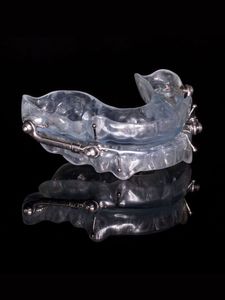 A clear mouth guard is sitting on a black surface.