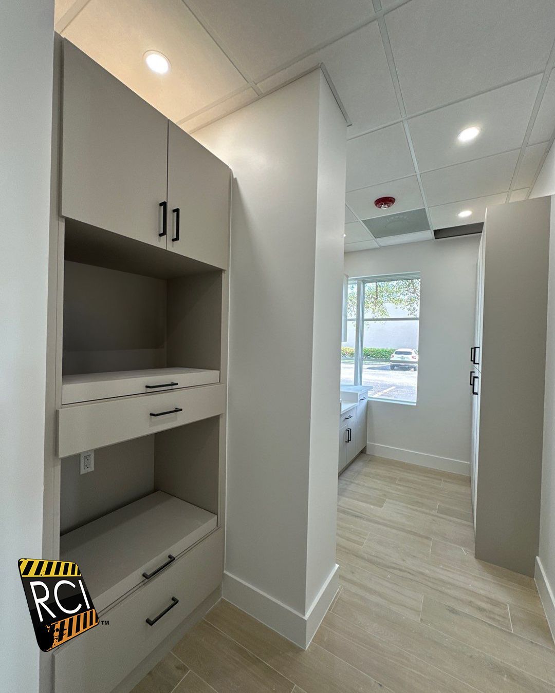 A room with a lot of cabinets and drawers and a window