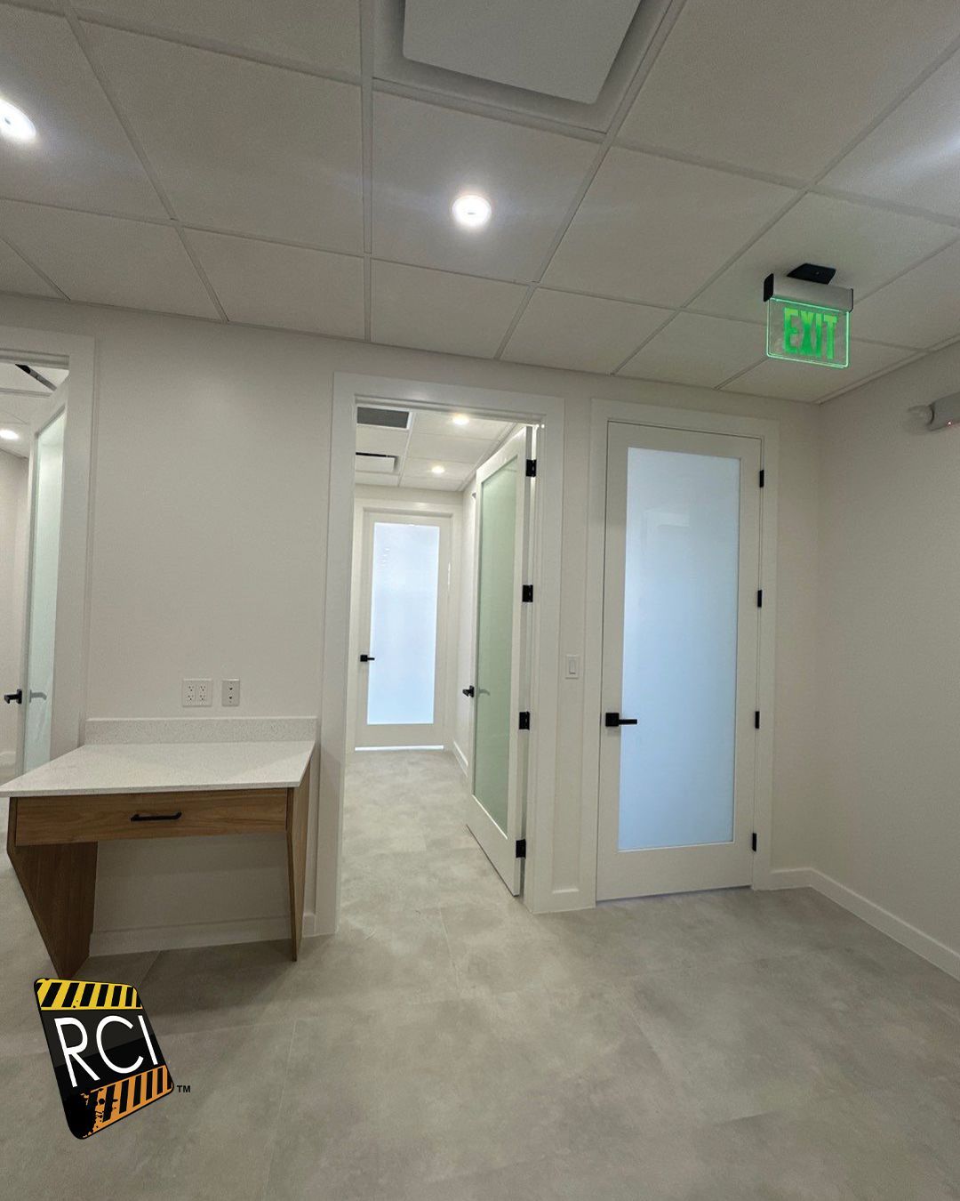 An empty room with a green exit sign on the ceiling