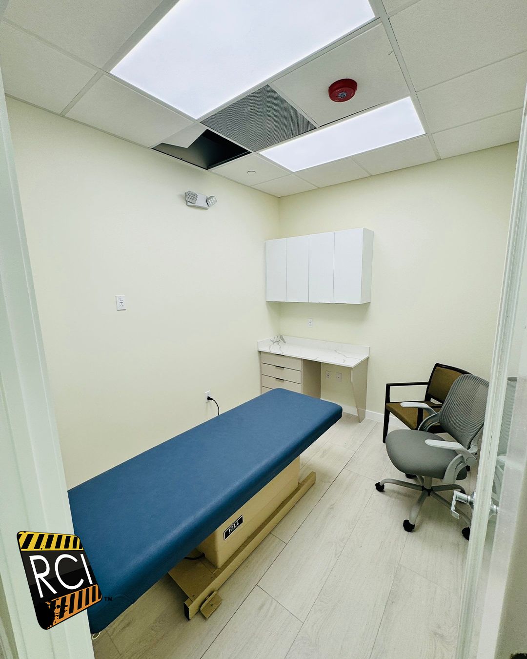 A doctor 's office with a blue bed and a chair.