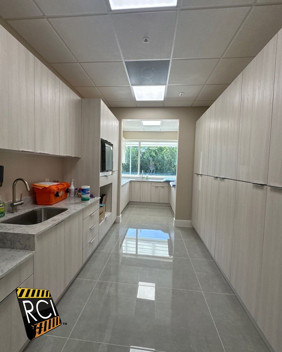A long hallway in a kitchen with a sink and cabinets