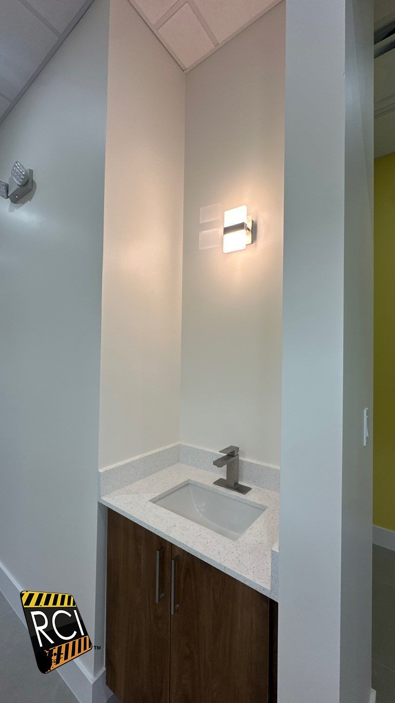 A bathroom with a sink and a light on the wall.