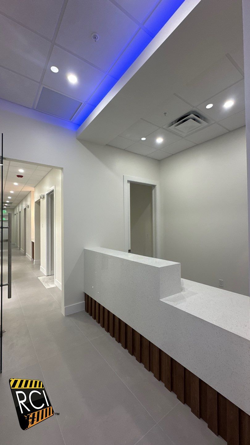A reception desk in a hallway with blue lights on the ceiling.