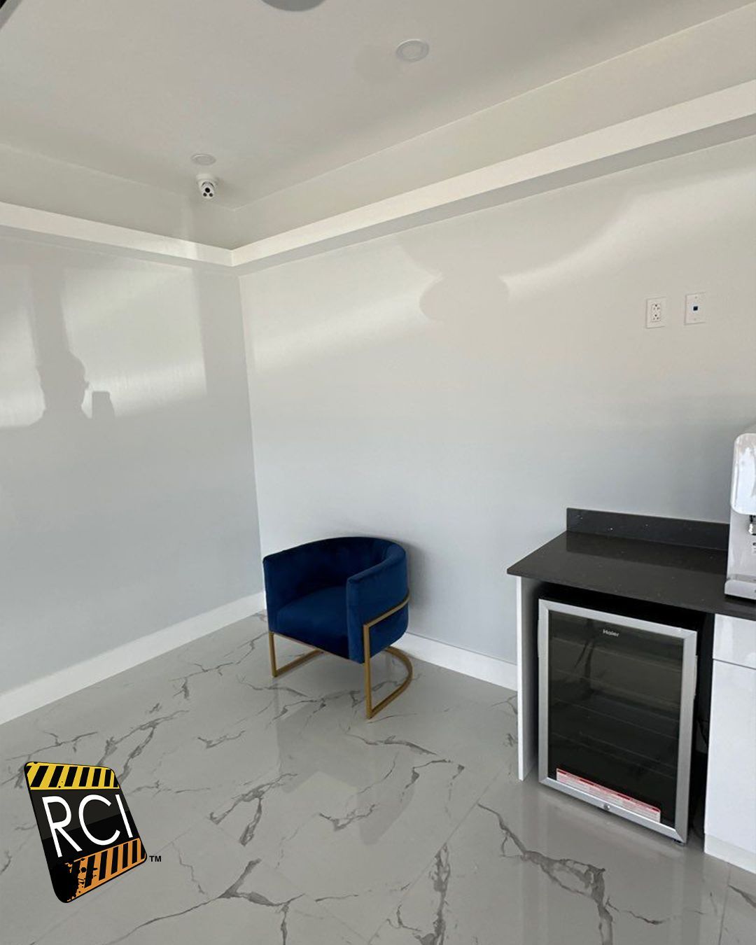 A room with a blue chair and a refrigerator.