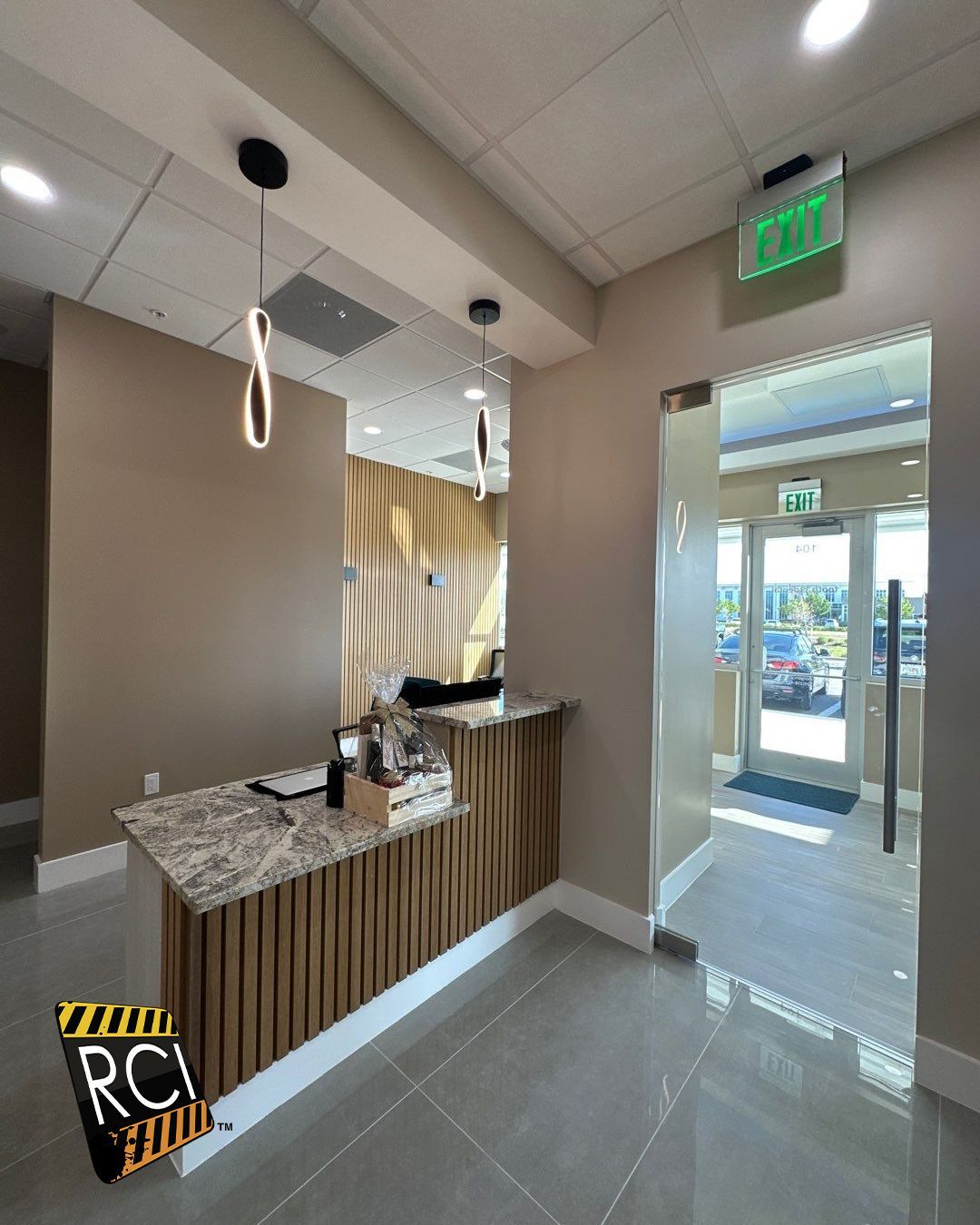 A lobby with a wooden counter and a green exit sign.