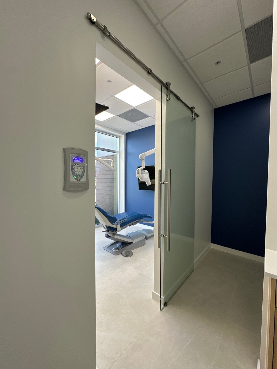 A dental office with a sliding glass door and a dental chair.