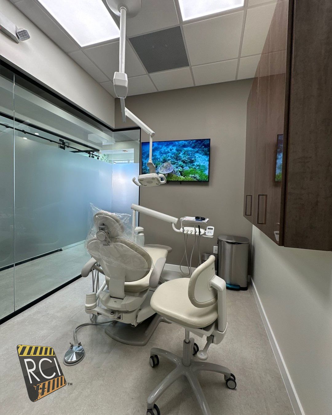 A dental office with a dental chair and a television on the wall.