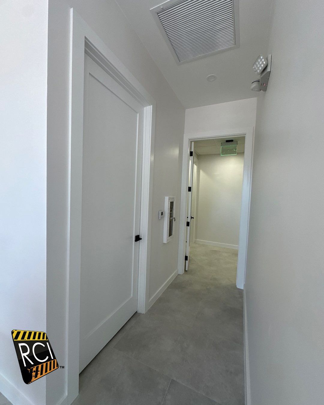 A hallway with white walls and a ceiling fan