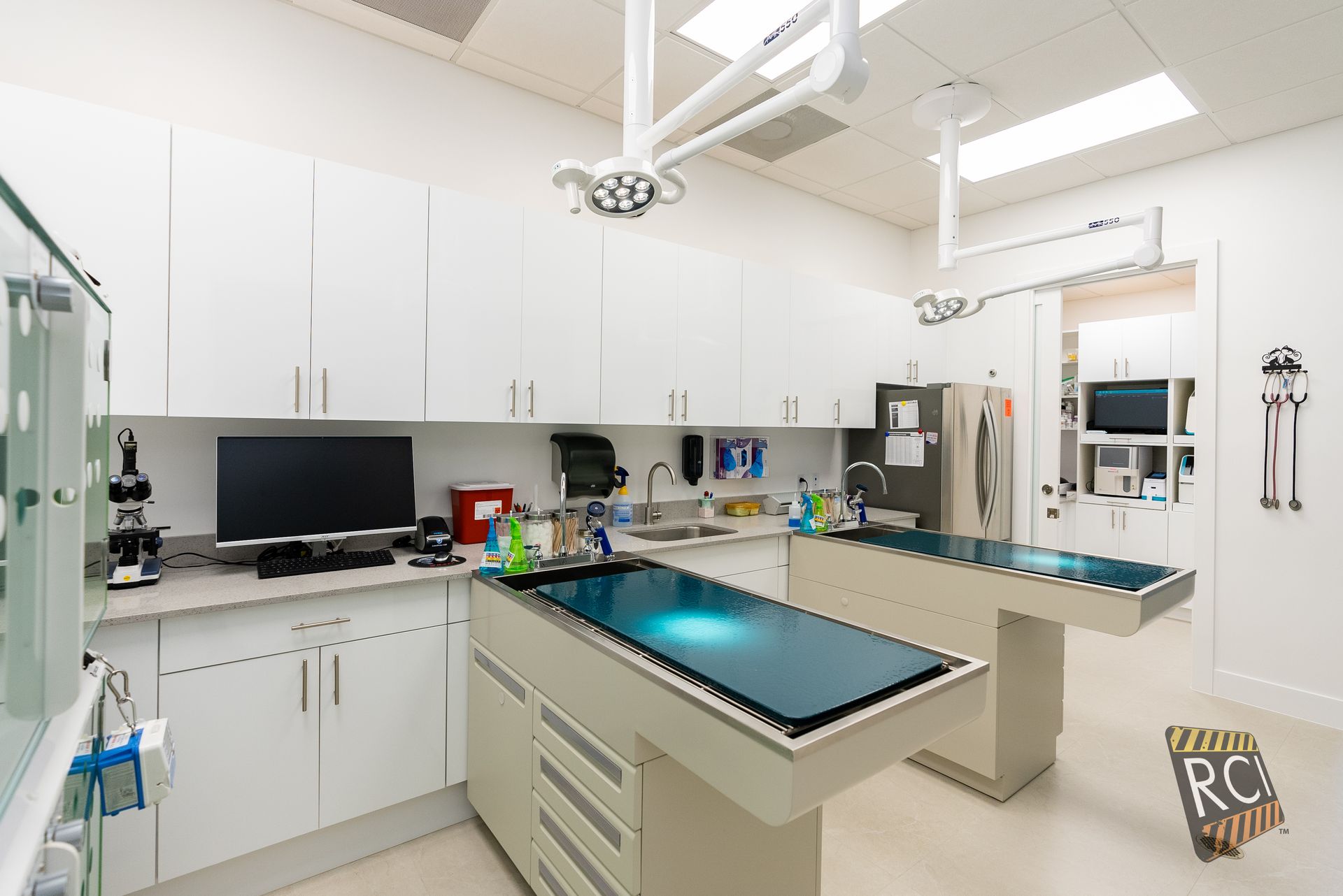 A veterinary operating room with a blue table and white cabinets