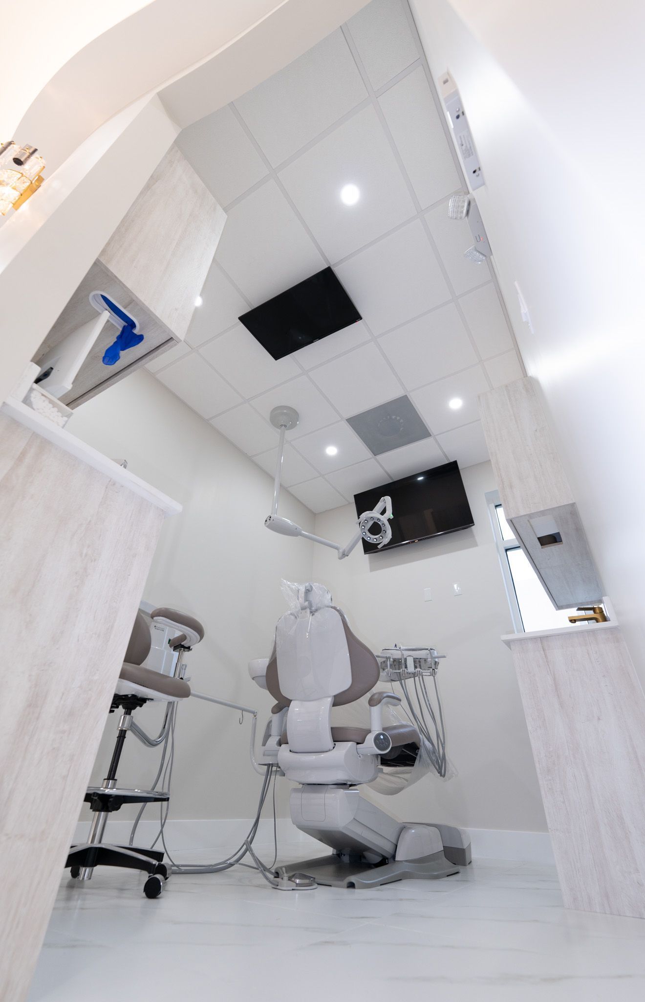 A dental office with a dental chair and a stool.