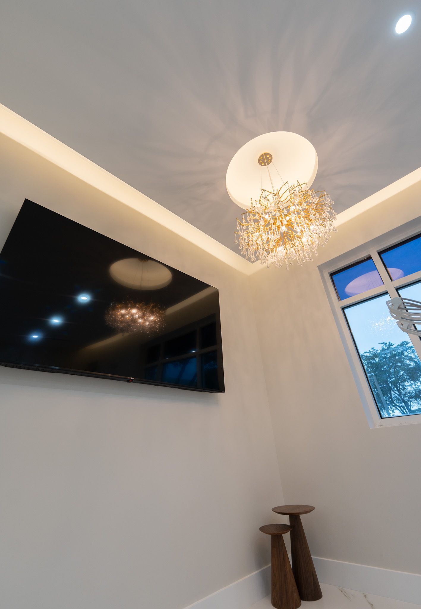A living room with a flat screen tv and a chandelier hanging from the ceiling.