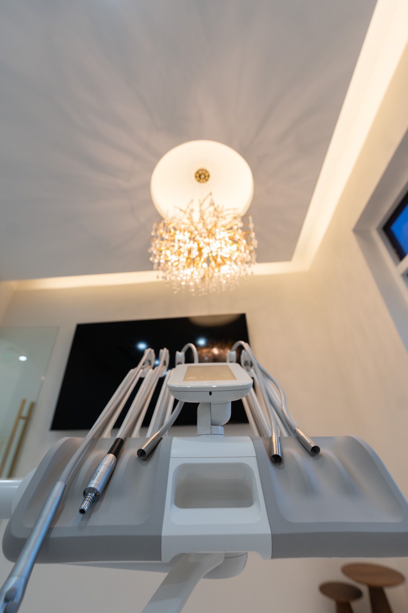A dental chair with a chandelier hanging from the ceiling in a dental office.