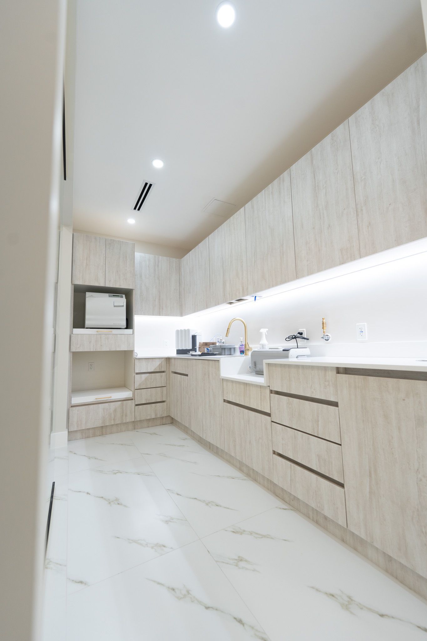 A kitchen with wooden cabinets and marble floors