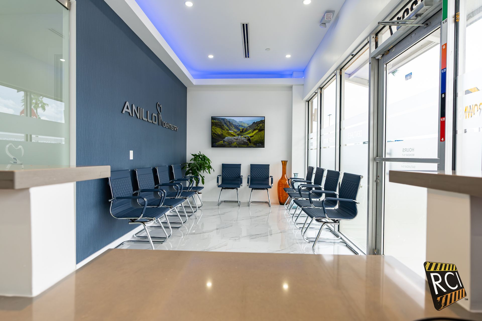 A waiting room with a lot of chairs and a tv on the wall.
