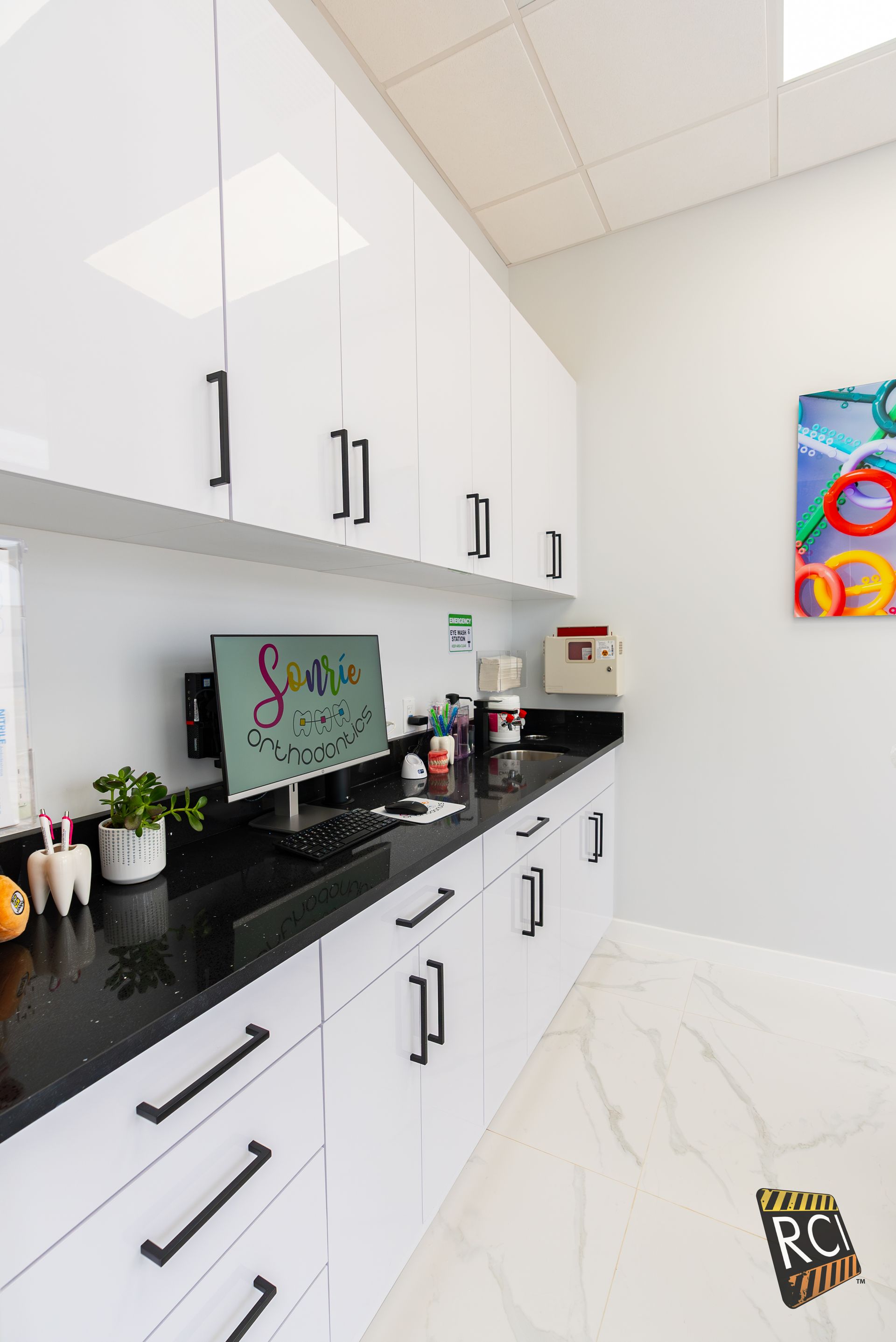 A kitchen with white cabinets and a computer on the counter.