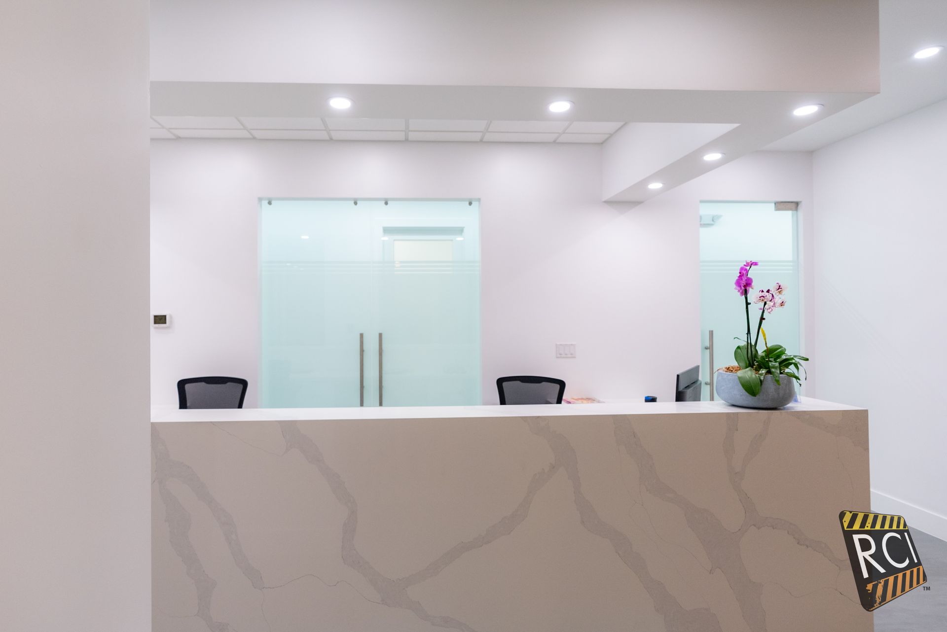 A reception desk in an office with a vase of flowers on it.