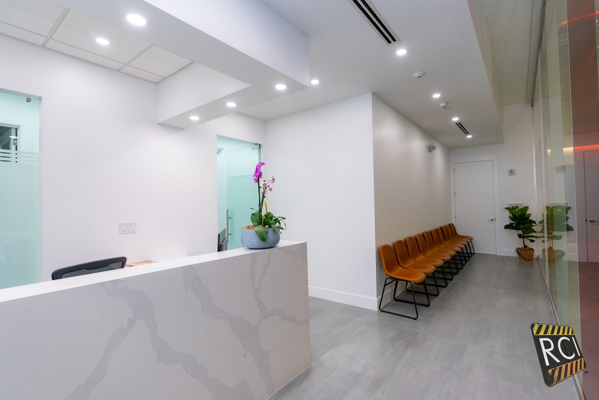 A waiting room with a reception desk and a row of chairs.