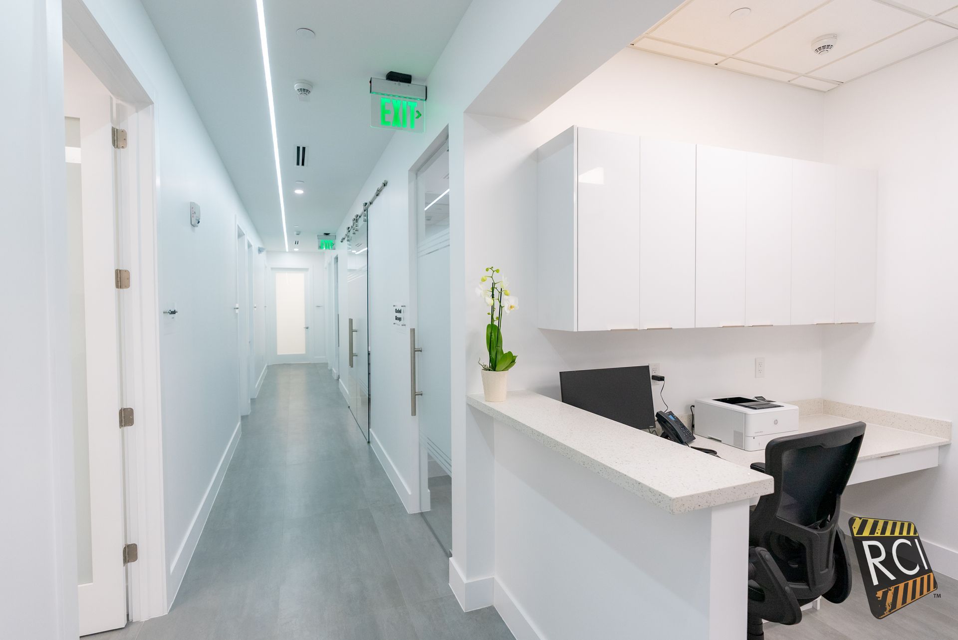A long hallway with a desk in the middle of it.