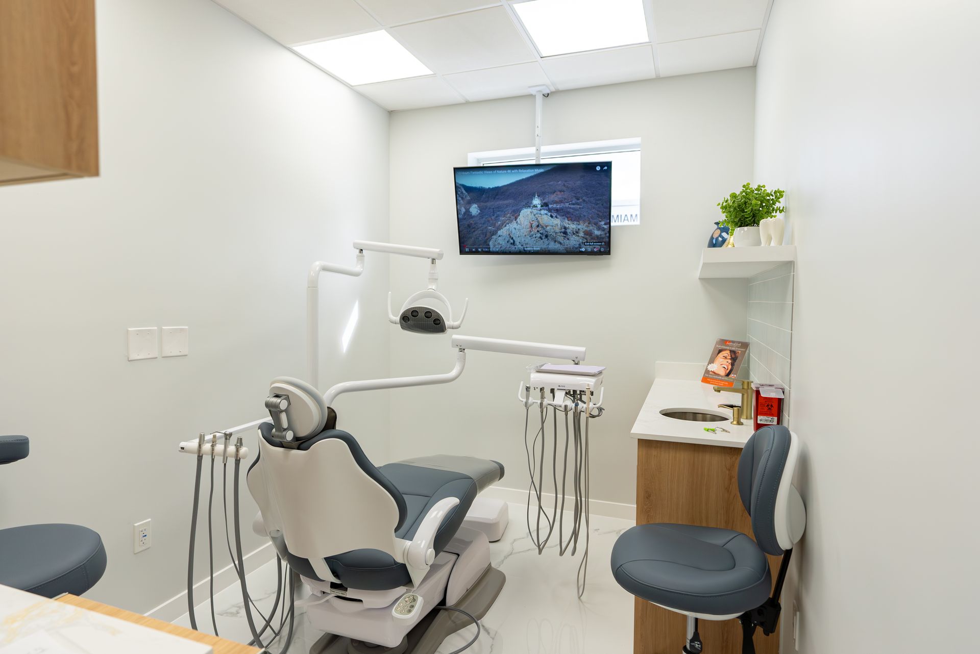 A dental office with a dental chair and a television on the wall.