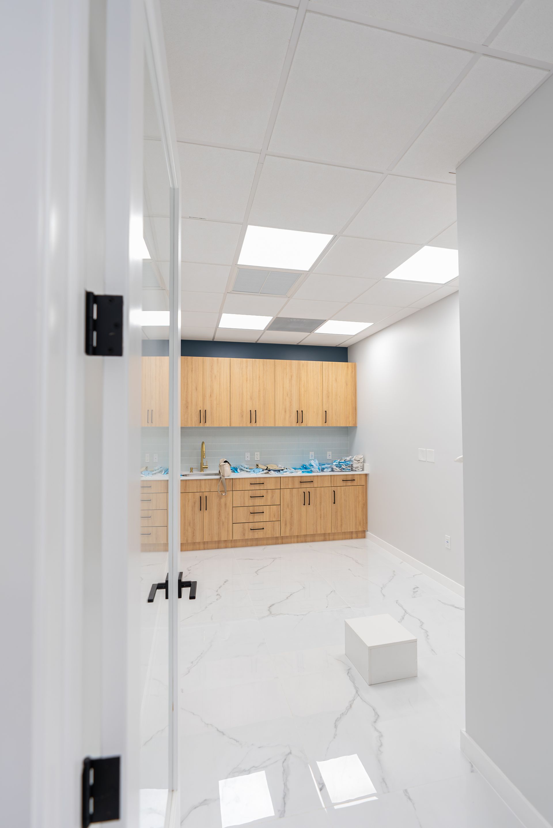 A kitchen with wooden cabinets and white tile floors in an empty room.