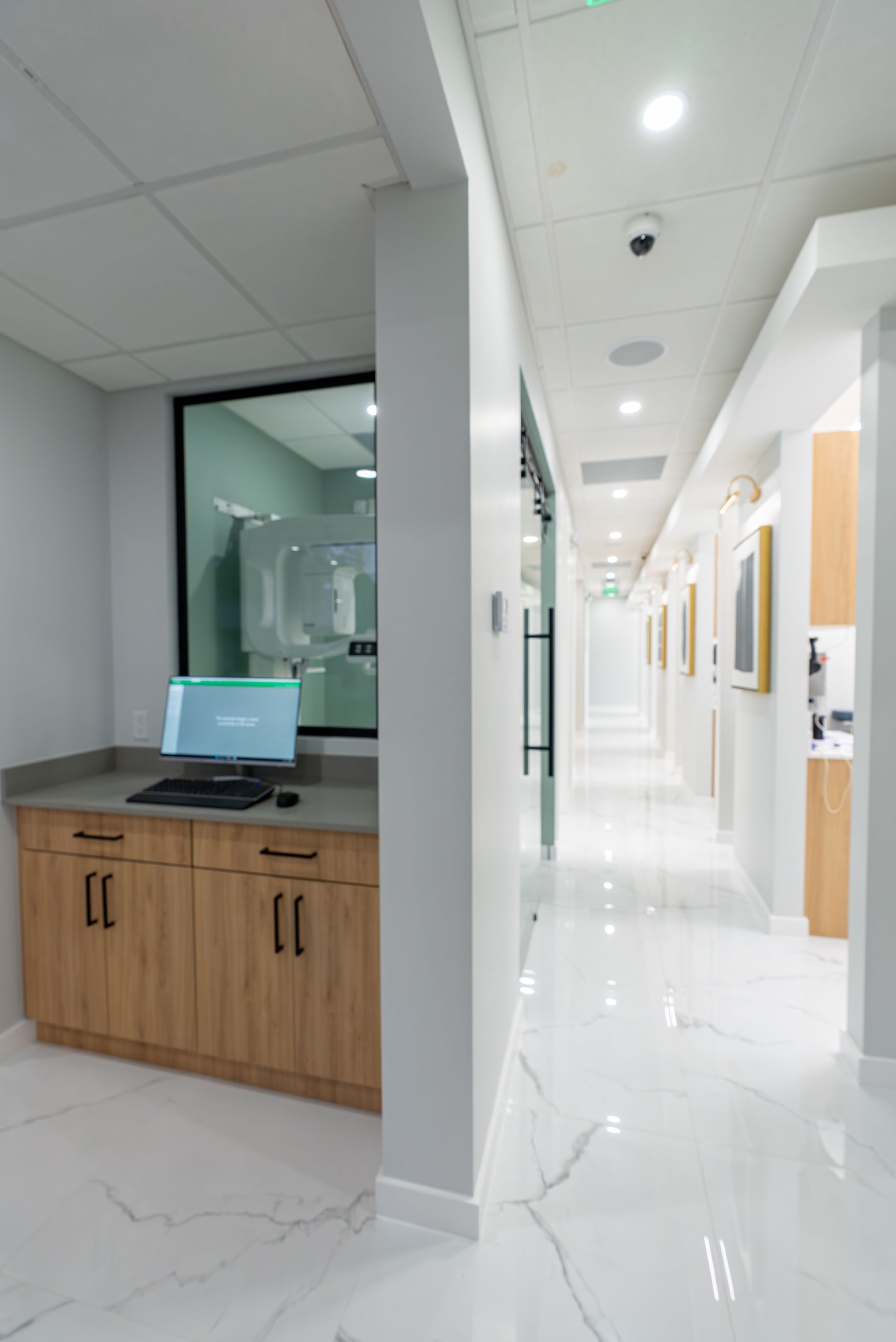 A long hallway in a dental office with a computer on a counter.