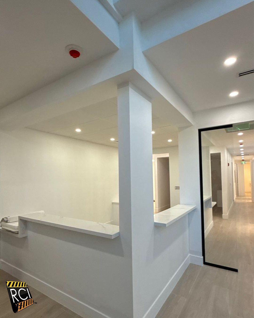 White reception area with a hallway, countertop, and column.