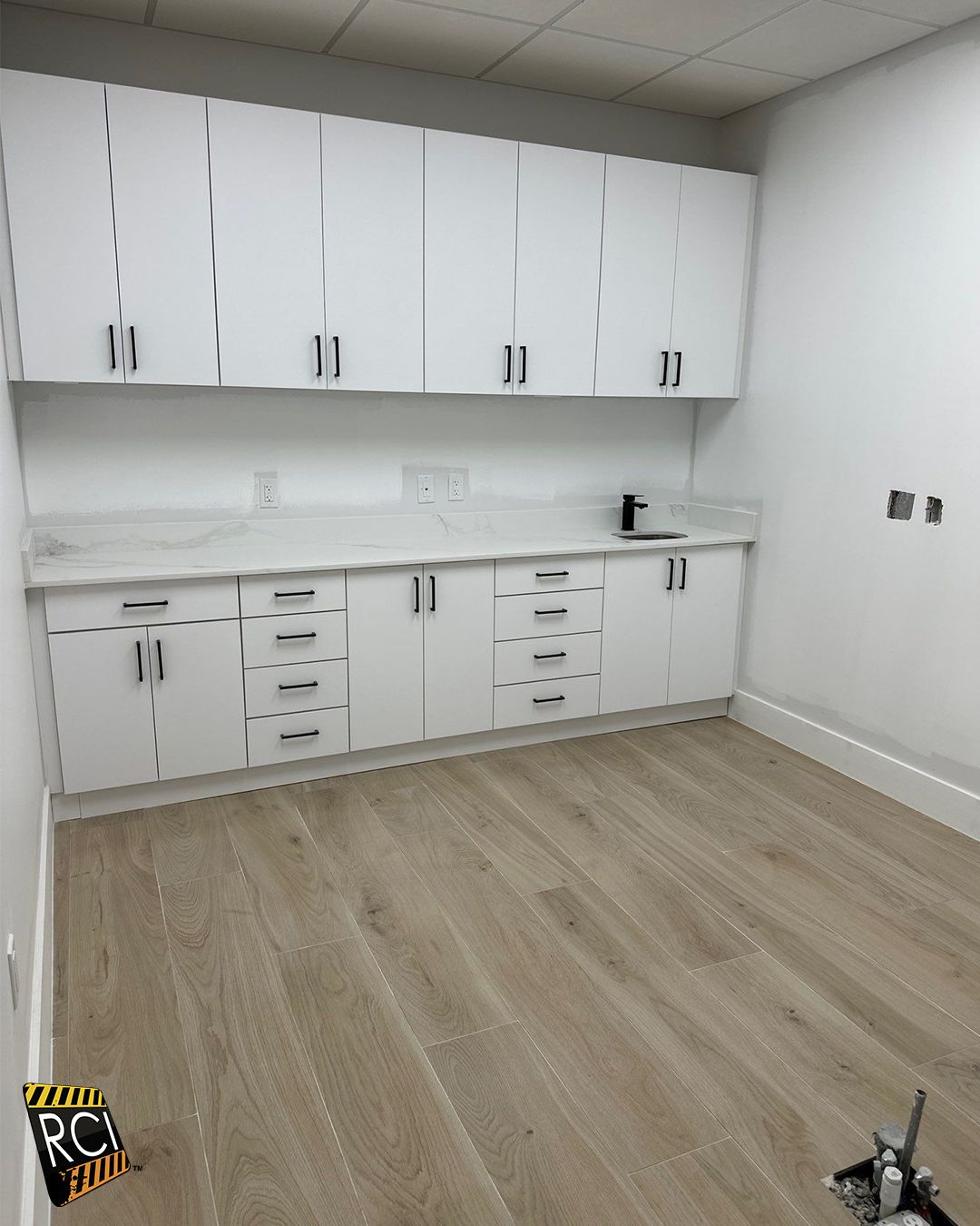 White cabinets and countertop in a room with light wood-look flooring.