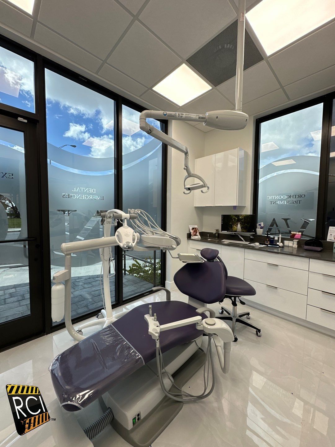 A dental office with a purple dental chair and a lot of windows