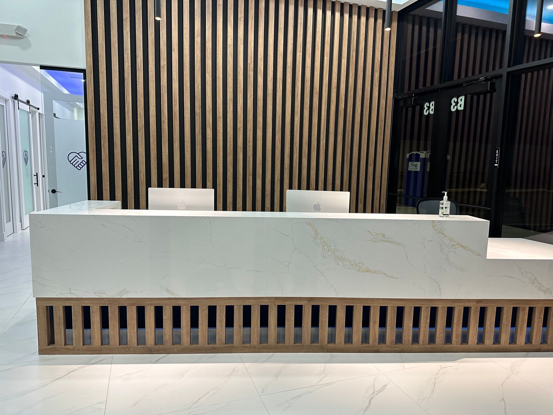 A white reception desk in a room with a wooden wall.