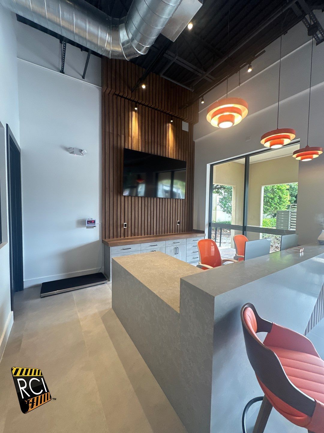 A kitchen with a bar and chairs and a tv on the wall
