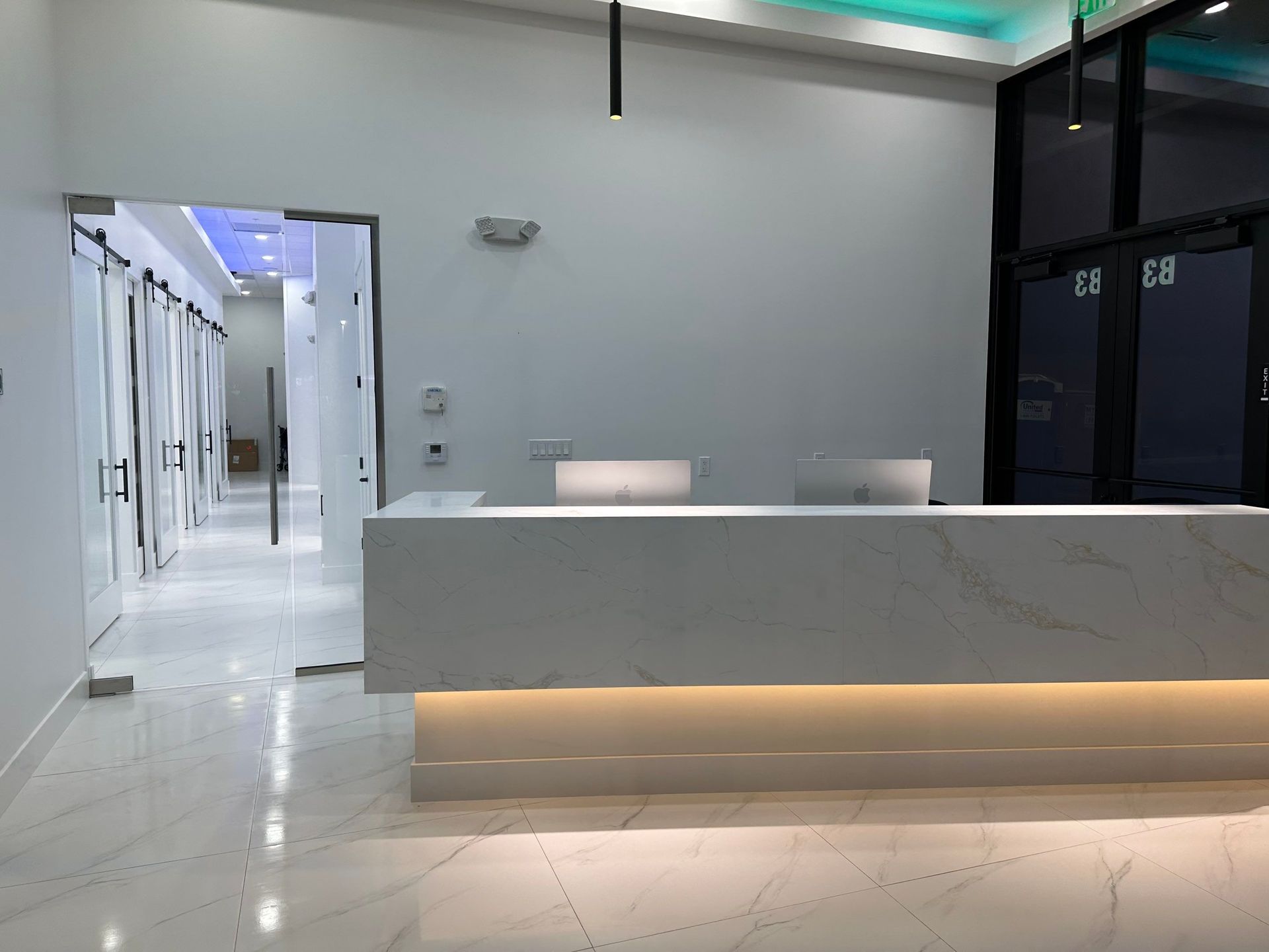 A white reception desk in a hospital with a computer on it.