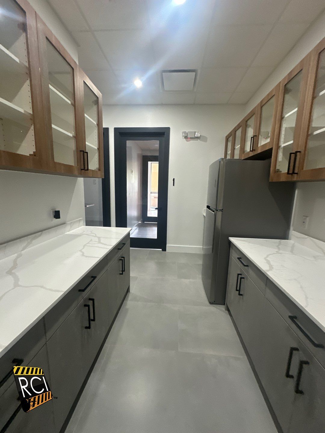 A kitchen with a refrigerator , sink , cabinets and counter tops.