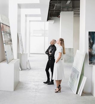 A man and a woman are looking at paintings in a museum.