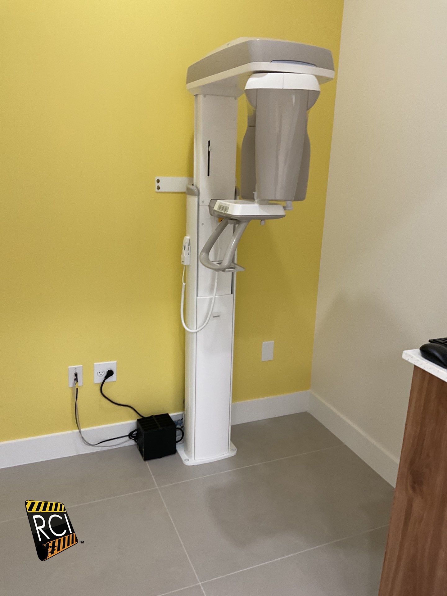 An x-ray machine is sitting in a room with a yellow wall.