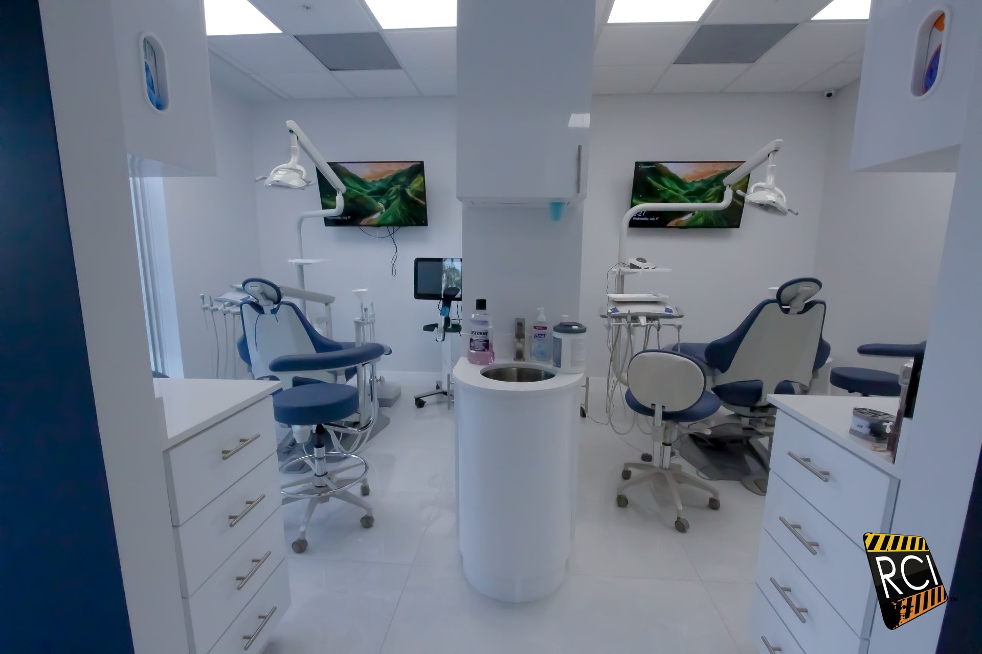 A dental office with a lot of dental chairs and a sink.