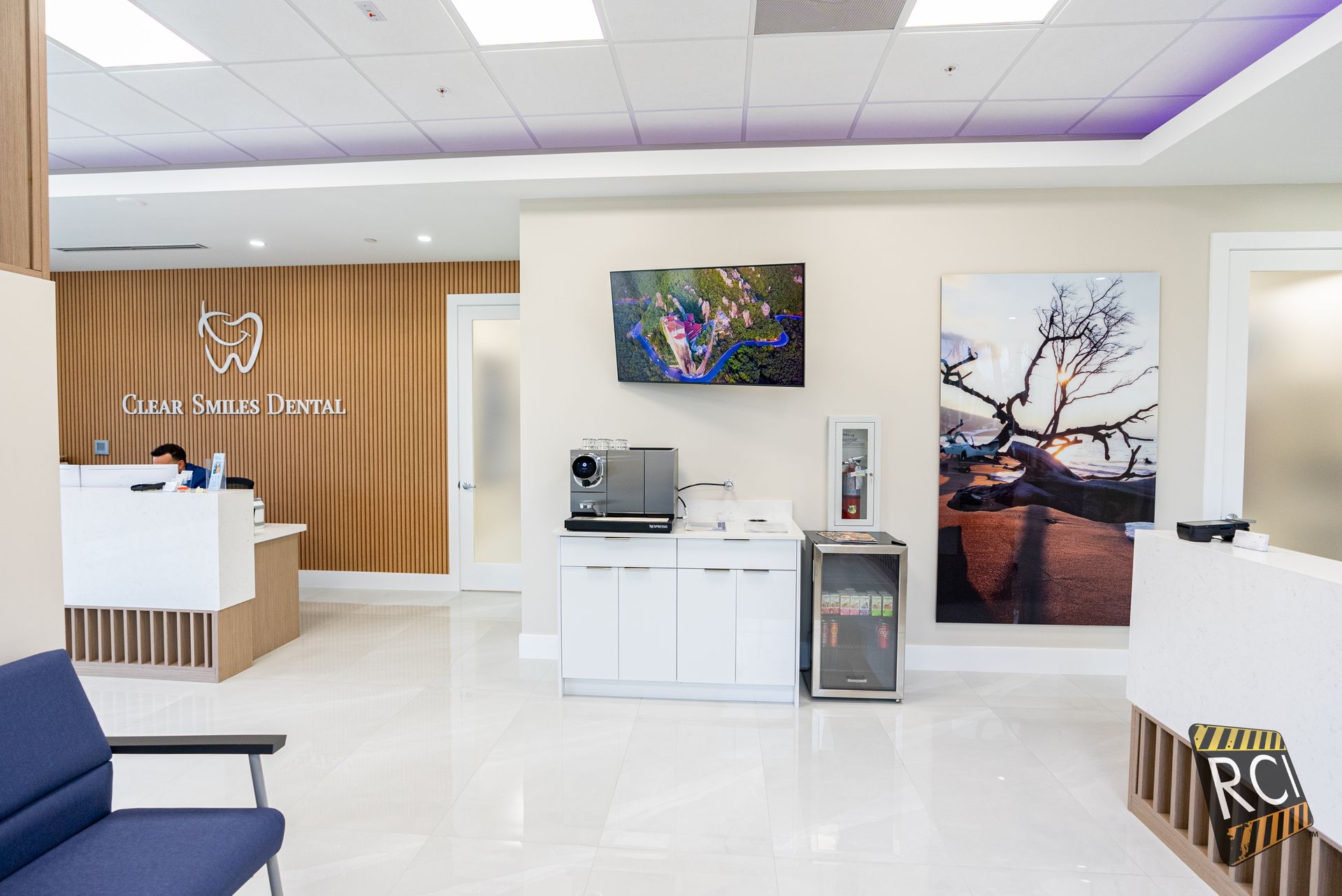 Dental office reception area with wood paneling, white counters, and artwork.
