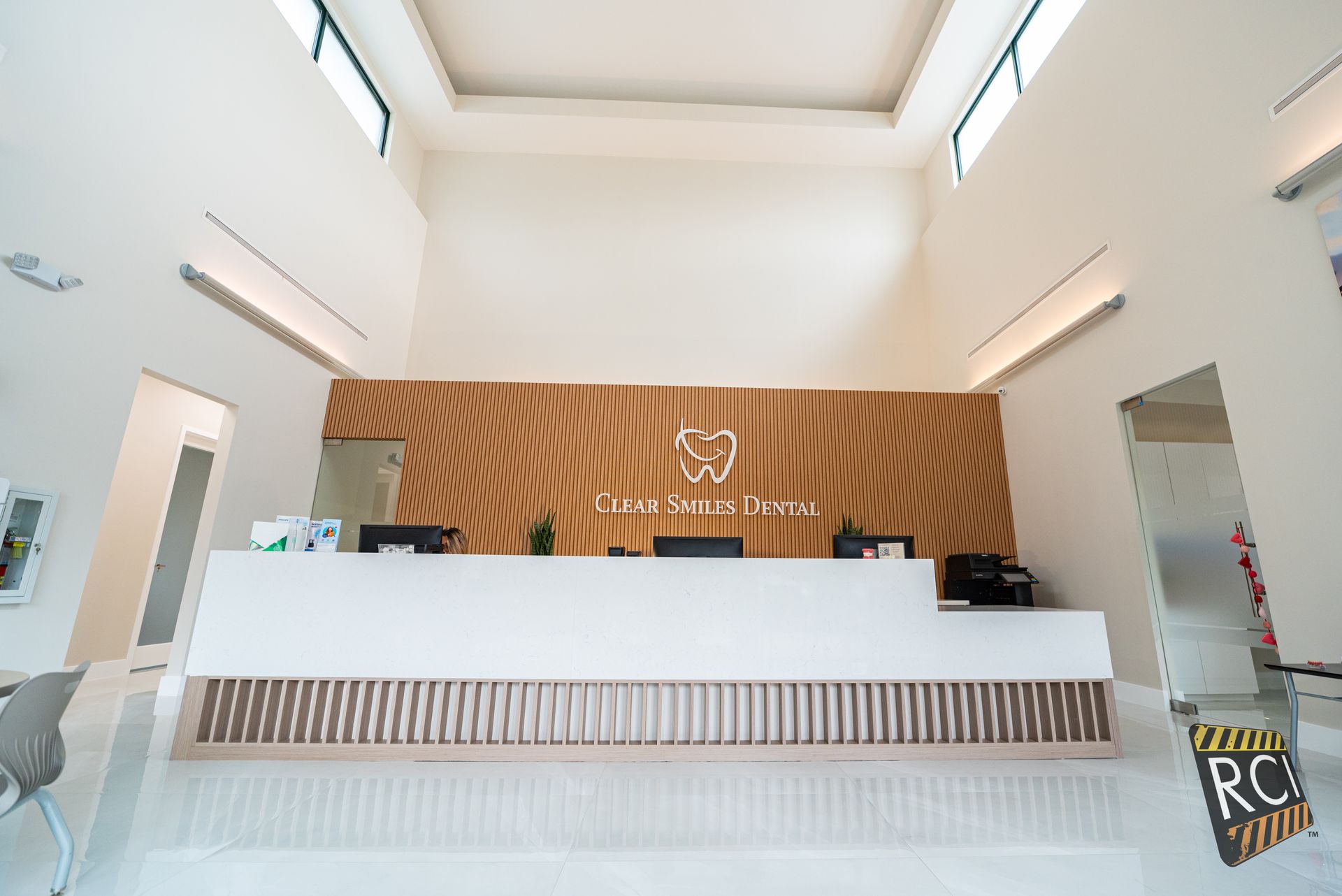Reception desk with wooden paneling and white countertop in a bright, modern space.