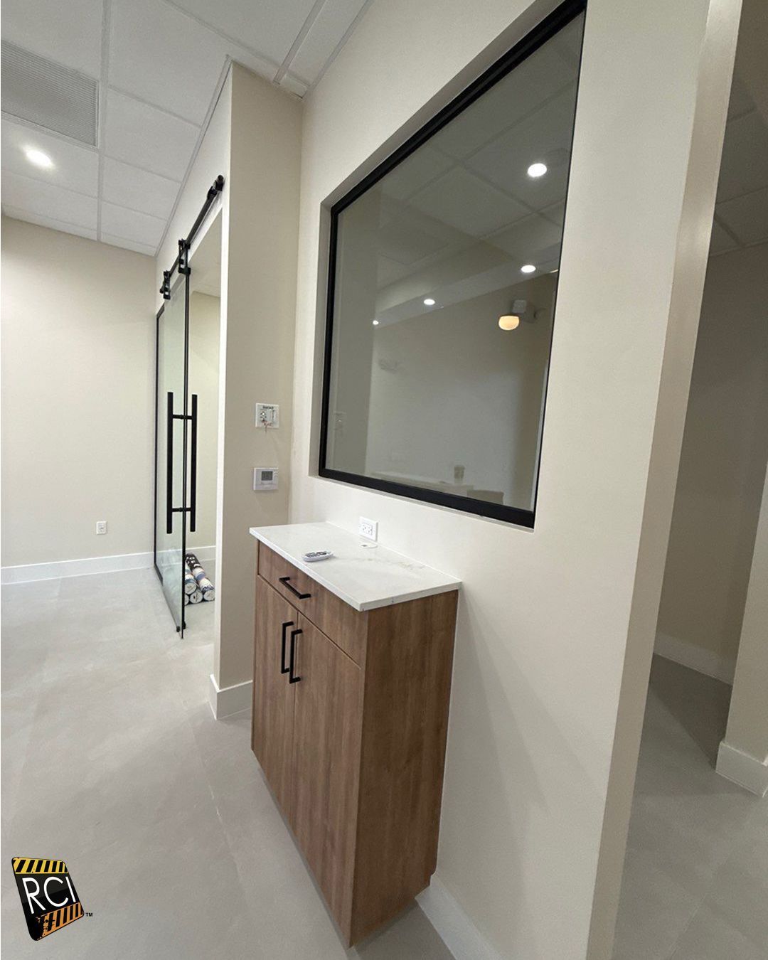 A hallway with a glass door and a green exit sign.