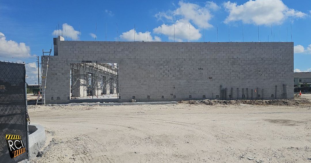 Construction site: cinder block building under construction, blue sky background.