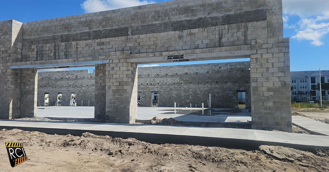 Unfinished concrete building with large openings and blue sky.