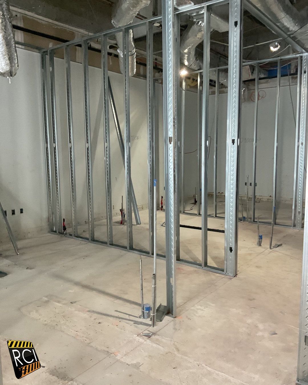 Metal studs frame interior walls in a construction site with concrete floor.