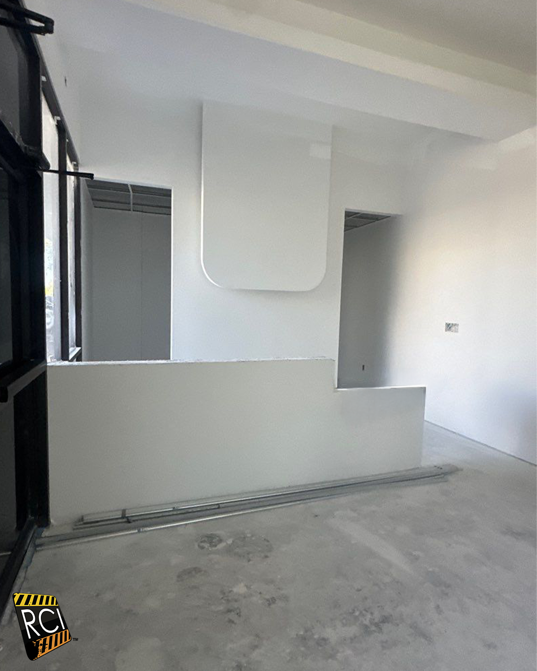 Interior of a room under construction with a white curved feature. Concrete floor and unfinished walls.