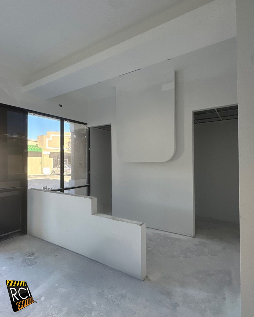 Interior room with white walls, unfinished drywall, window, and door frames; concrete floor.