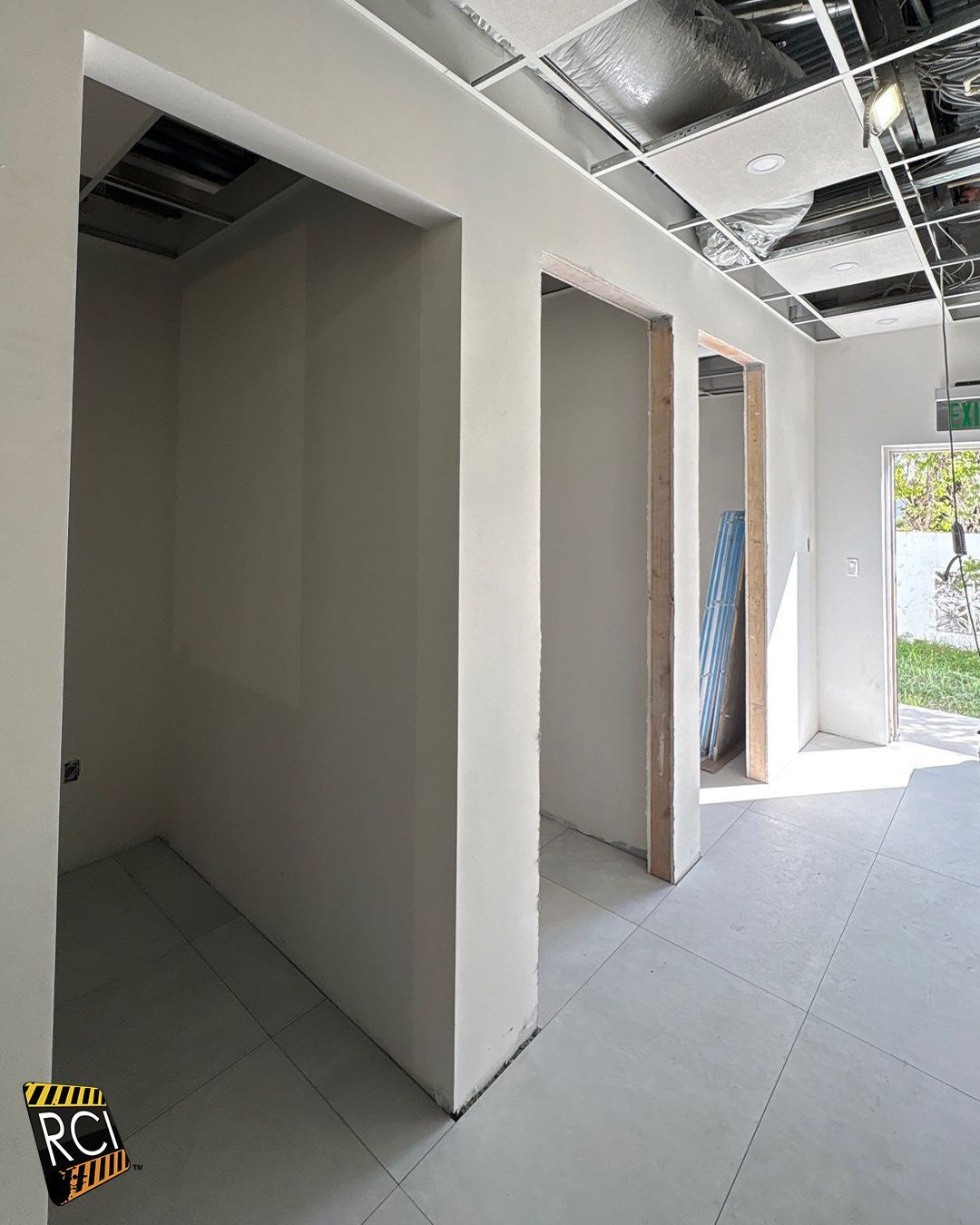 Interior view of unfinished construction with three doorways, white walls, and exposed ceiling.