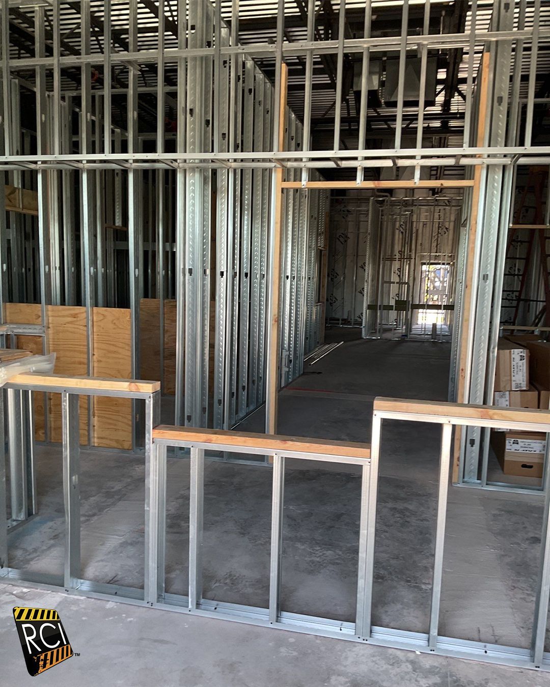 Interior steel framing of a building under construction, showing wall studs and doorway openings.