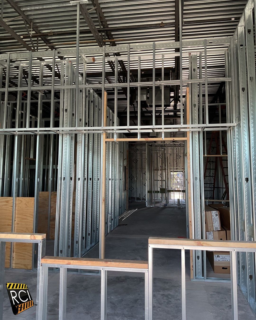 Interior view of a building under construction, showing metal framing and doorway.