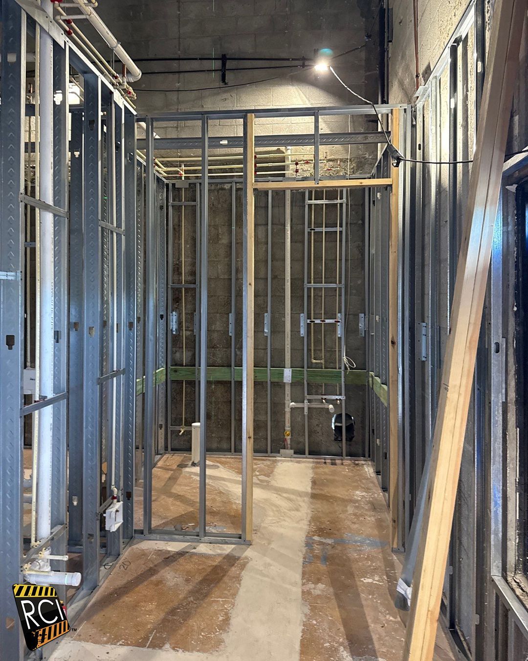 Interior hallway under construction with metal studs and exposed wiring.