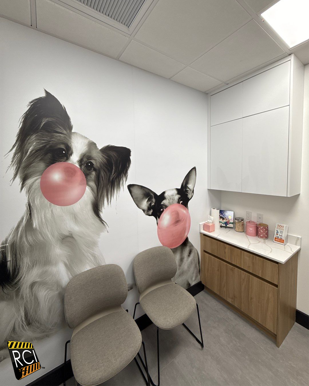 Waiting room with dog-themed mural, two chairs, and a countertop with supplies.