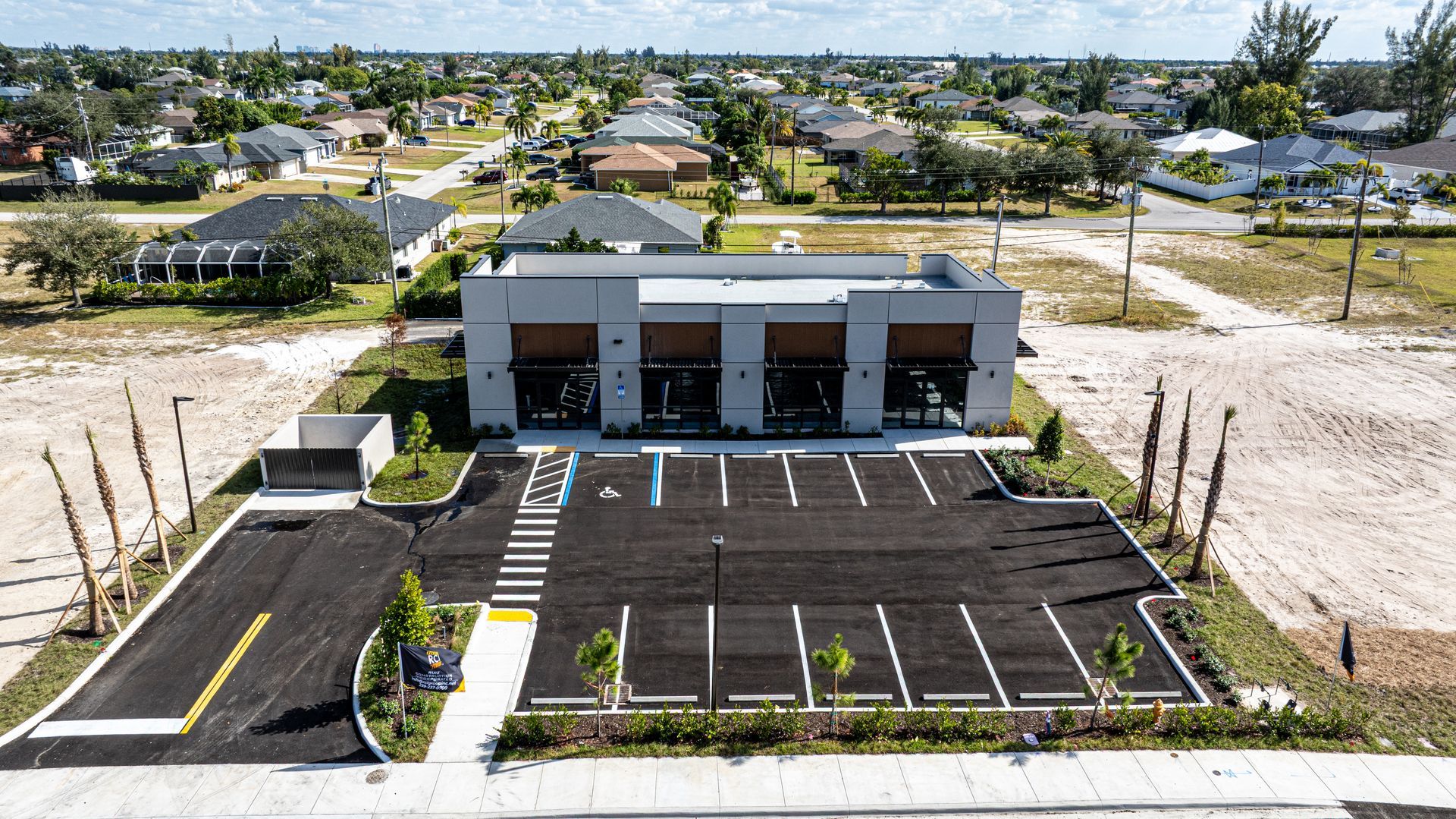 Fire station with a black asphalt parking lot, blue handicap spots, and a residential neighborhood in the background.