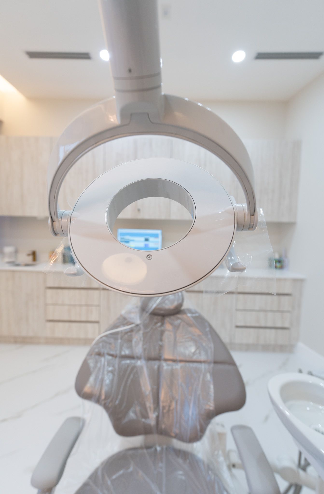 A dental chair with a light hanging from the ceiling in a dental office.